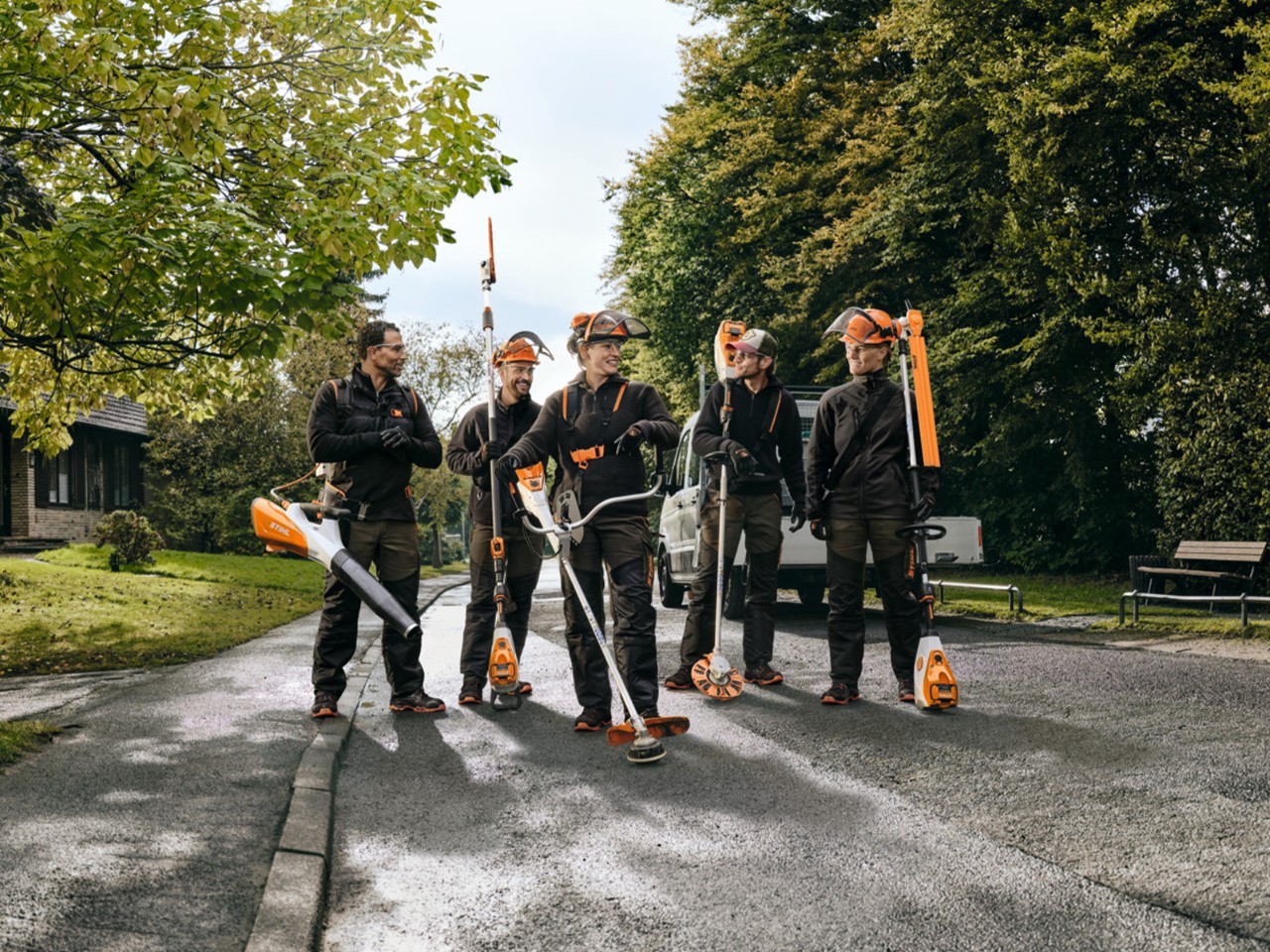 Eine Gruppe von Profis mit verschiedenen STIHL Akku-Geräten geht eine Straße entlang