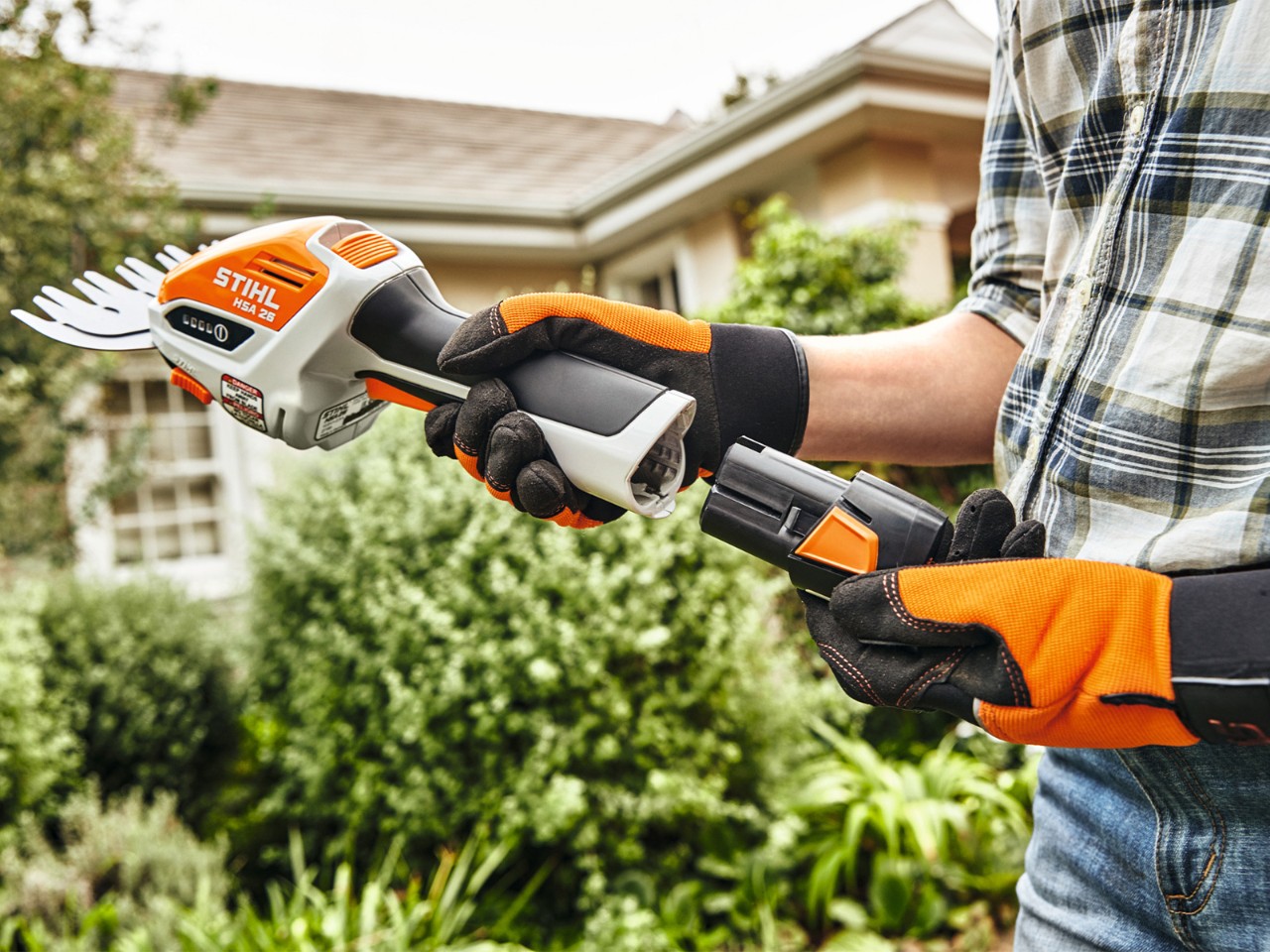 Frau, die den Akku STIHL AS 2 in die Akku-Strauchschere STIHL HSA 26 einsteckt.