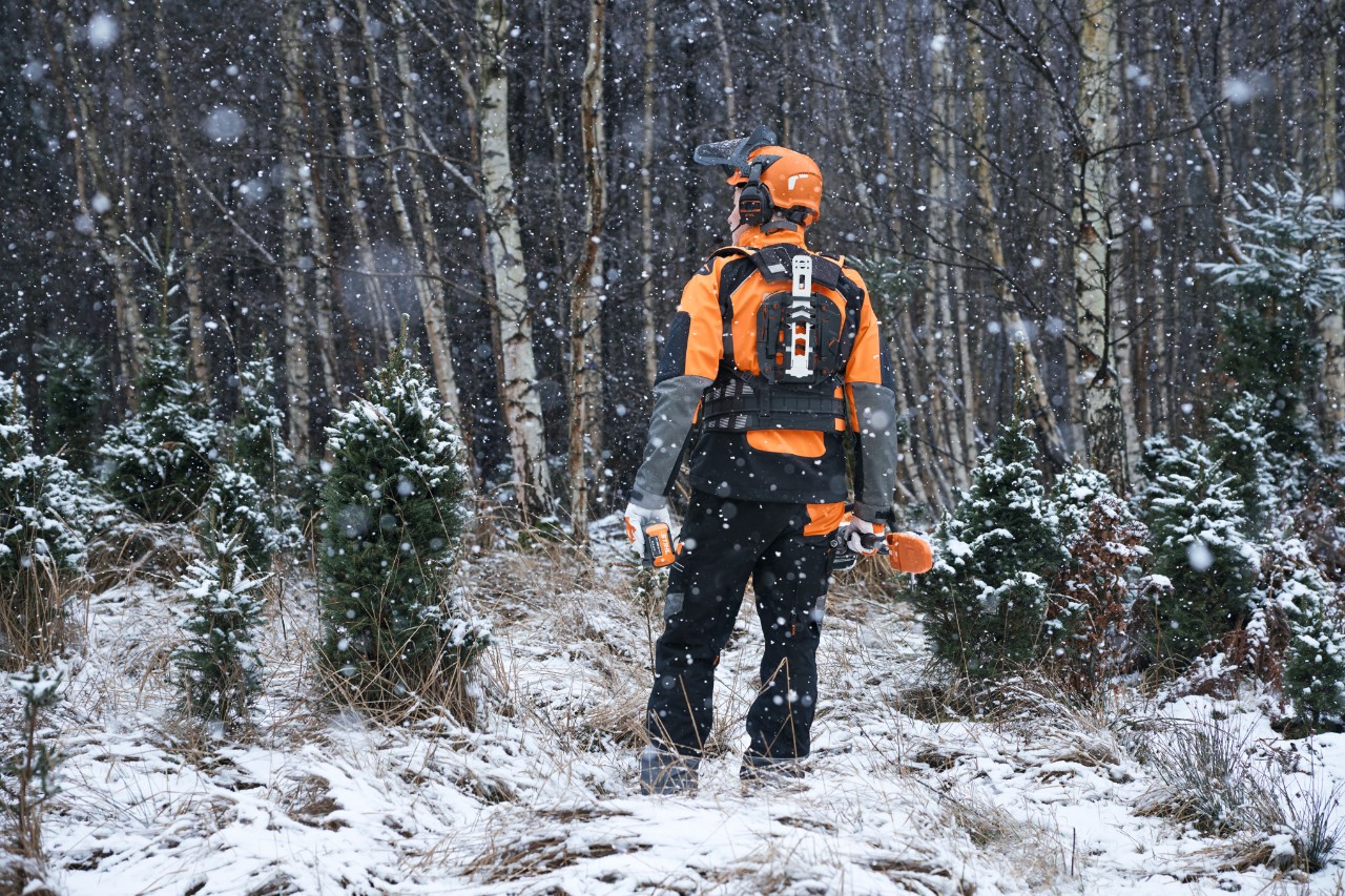 Waldarbeiter mit wetterfester PSA Forst im verschneiten Waldgebiet