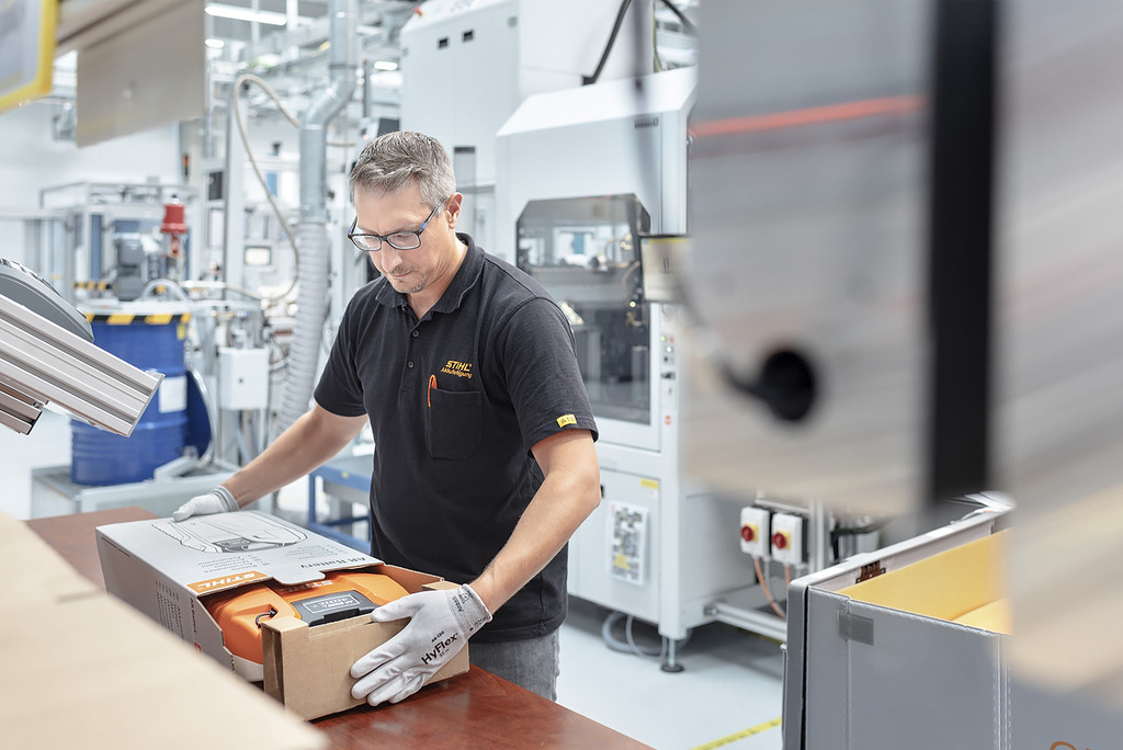 Ein Angestellter in der Akkufertigung packt ein STIHL Akku-Gerät in einen Karton 