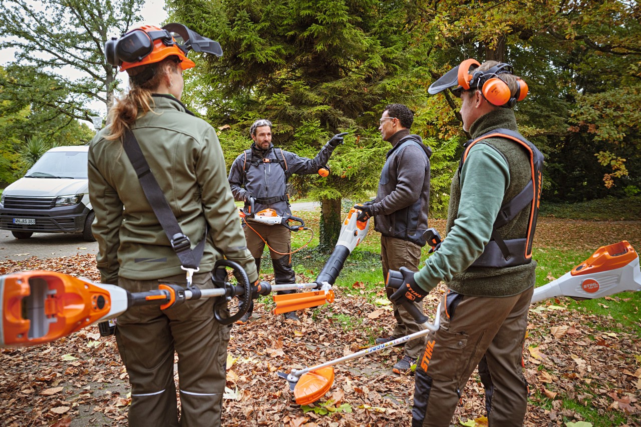 Vier Profis stehen mit Profigeräten an einer Waldlichtung.