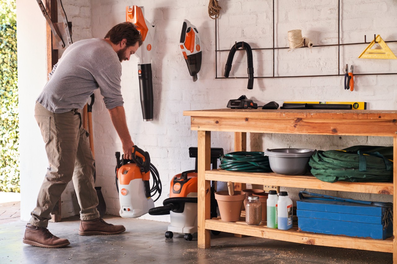 Ein Mann stellt einen Hochdruckreiniger STIHL RE 80 X in einer Werkstatt ab