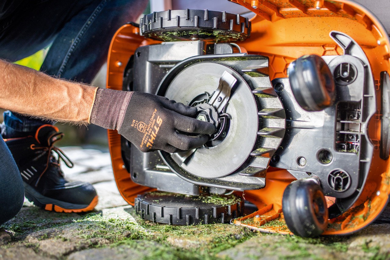 Auf der Seite liegender  STIHL iMOW® Mähroboter 422 wird vor der Winterpause auf Verschleiß geprüft