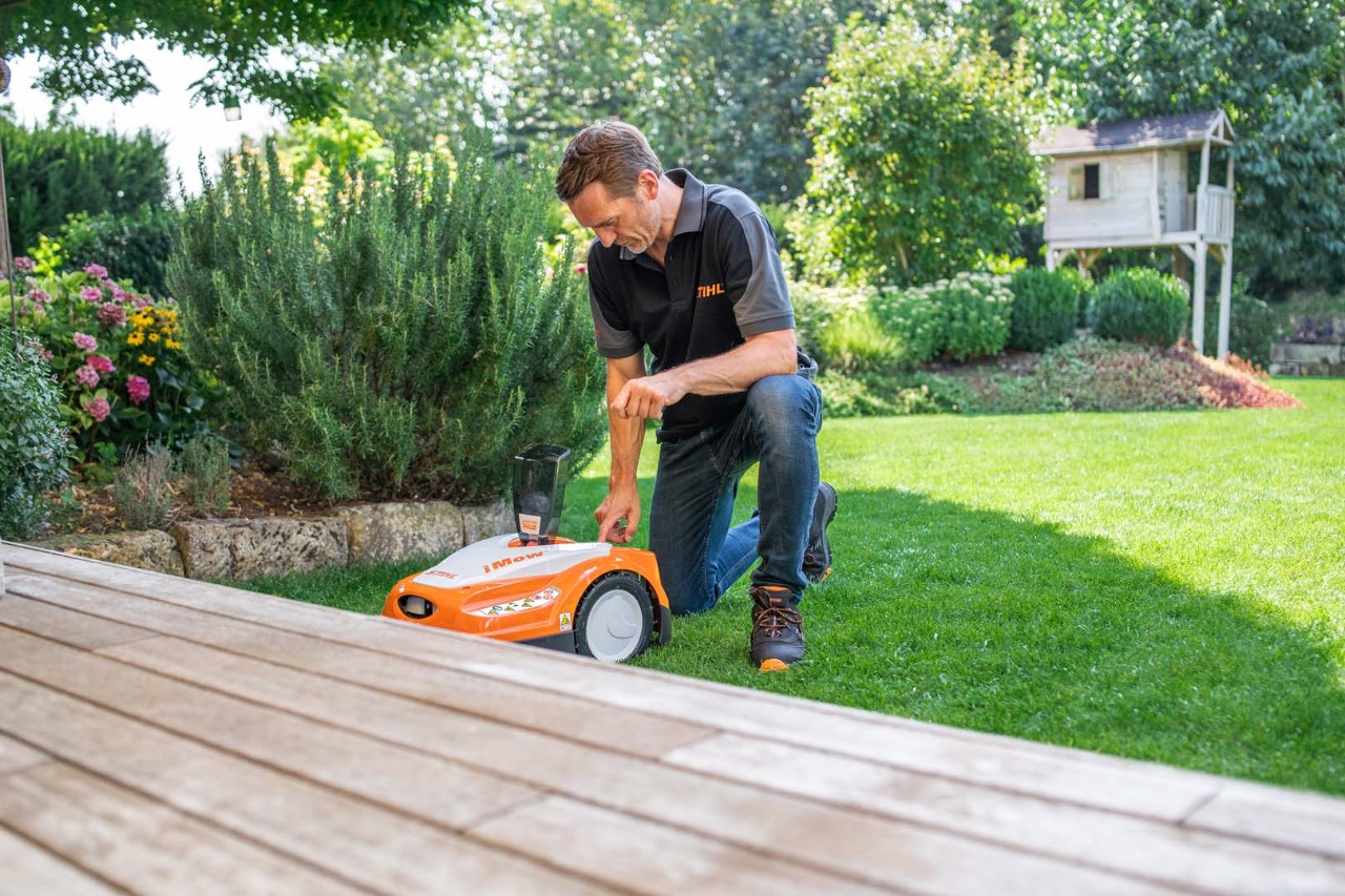  STIHL Fachhändler richtet den dynamischen Mähplan des STIHL iMOW® Mähroboters RMI 422 auf einem grünen Grundstück ein