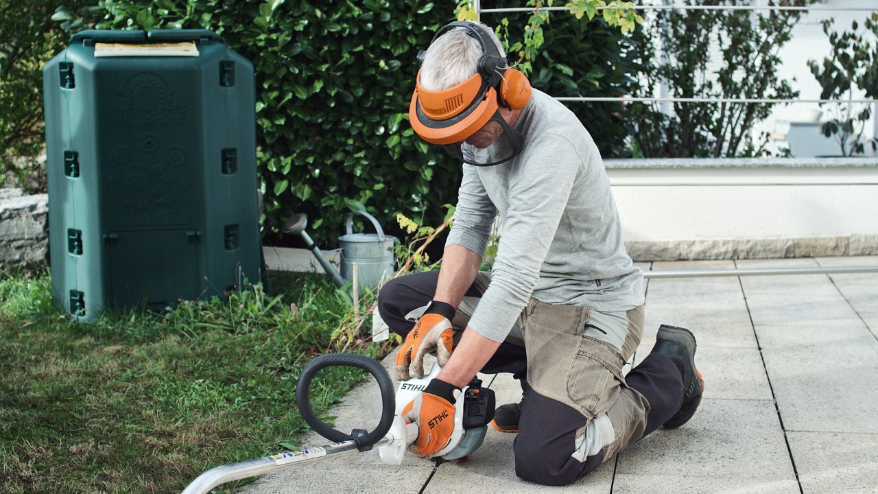 Benzin-Motorsense STIHL FS 38 wird von einer Person in Schutzkleidung auf den Boden gedrückt