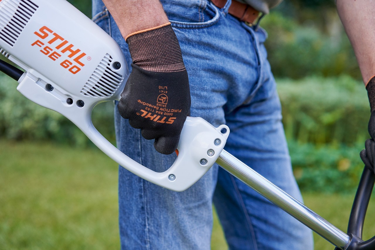 Mann drückt den Schalter am Bedienungsgriff der Elektro-Motorsense STIHL FSE 60