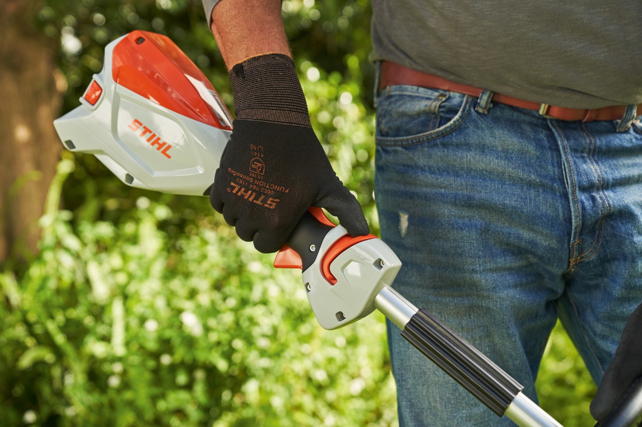 Mann mit Schutzhandschuhen schiebt den Entsperrschieber der Akku-Motorsense STIHL FSA 60 zum Rundumgriff