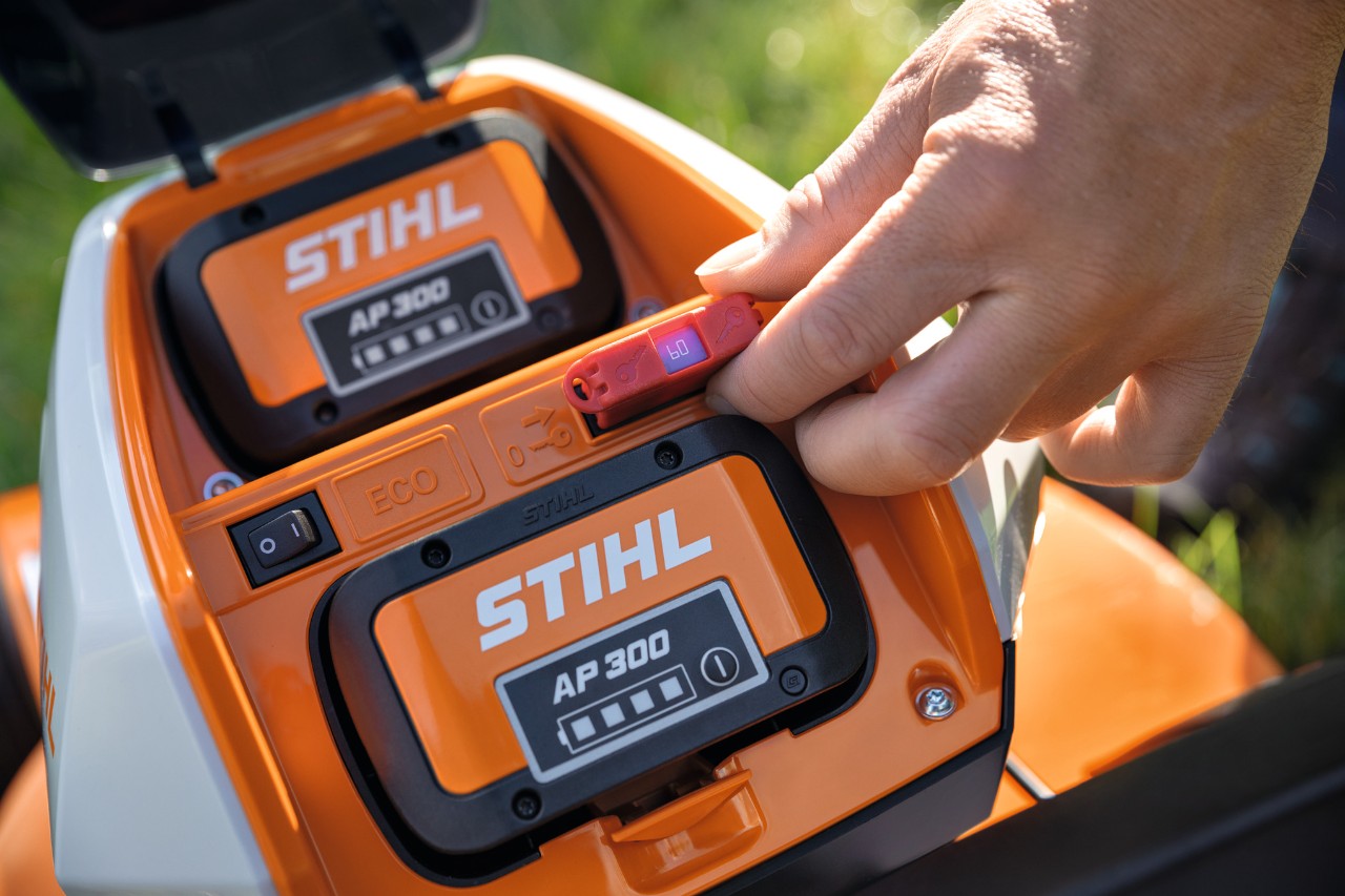 Eine Person steckt einen Sicherheitsstecker in den Akku-Rasenmäher STIHL RMA 448 VC ein 