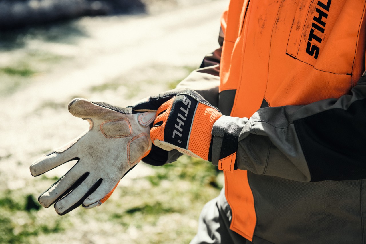 Person zieht sich STIHL Schutzhandschuhe an