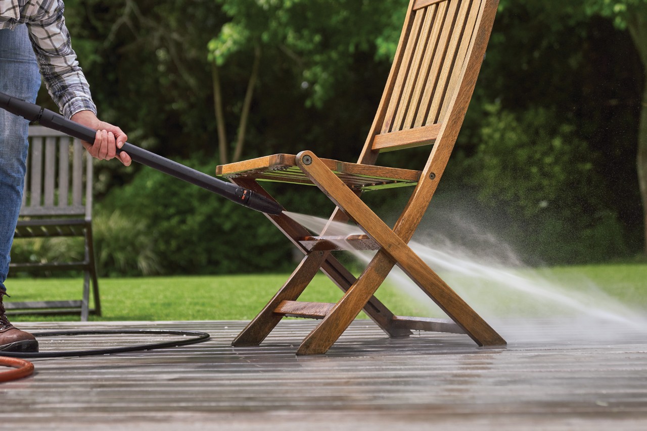 Gartenstuhl aus Holz wird auf einer Terrasse mit einem STIHL Hochdruckreiniger RE 130 plus gereinigt
