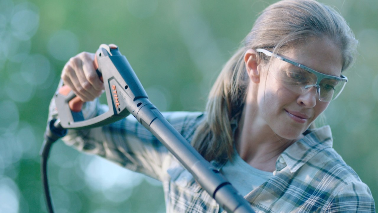 Frau reinigt Gartenmöbel mit einem STIHL Hochdruckreiniger RE 130 plus
