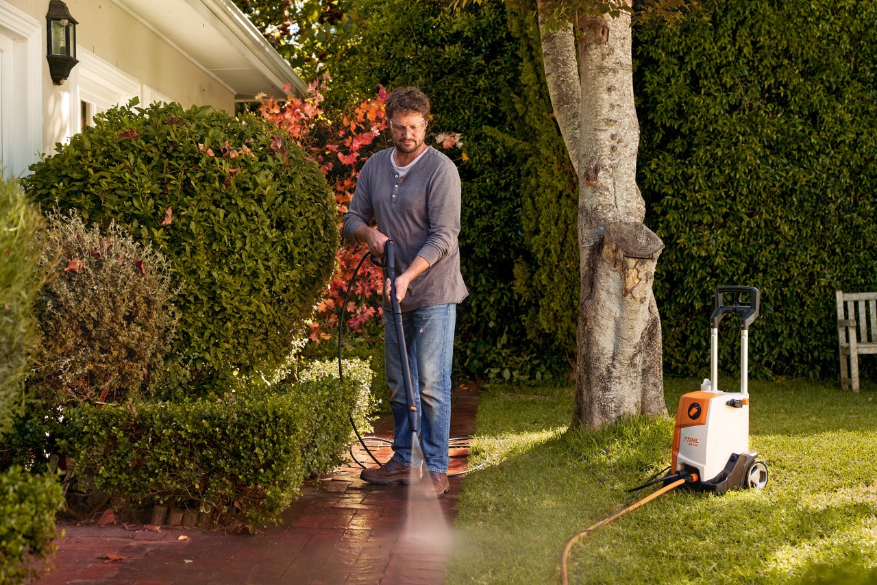 Mann reinigt die Pflastersteine in seinem Garten mit einem STIHL Hochdruckreiniger.