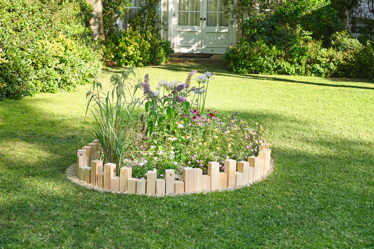 Rundbeet auf einem Gartengrundstück mit einer selber gemachten Beeteinfassung aus Holz