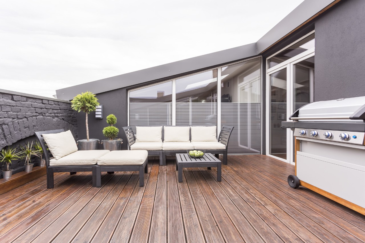 Gartenmöbel, Grill und Pflanzen auf einer Dachterrasse mit Holzboden