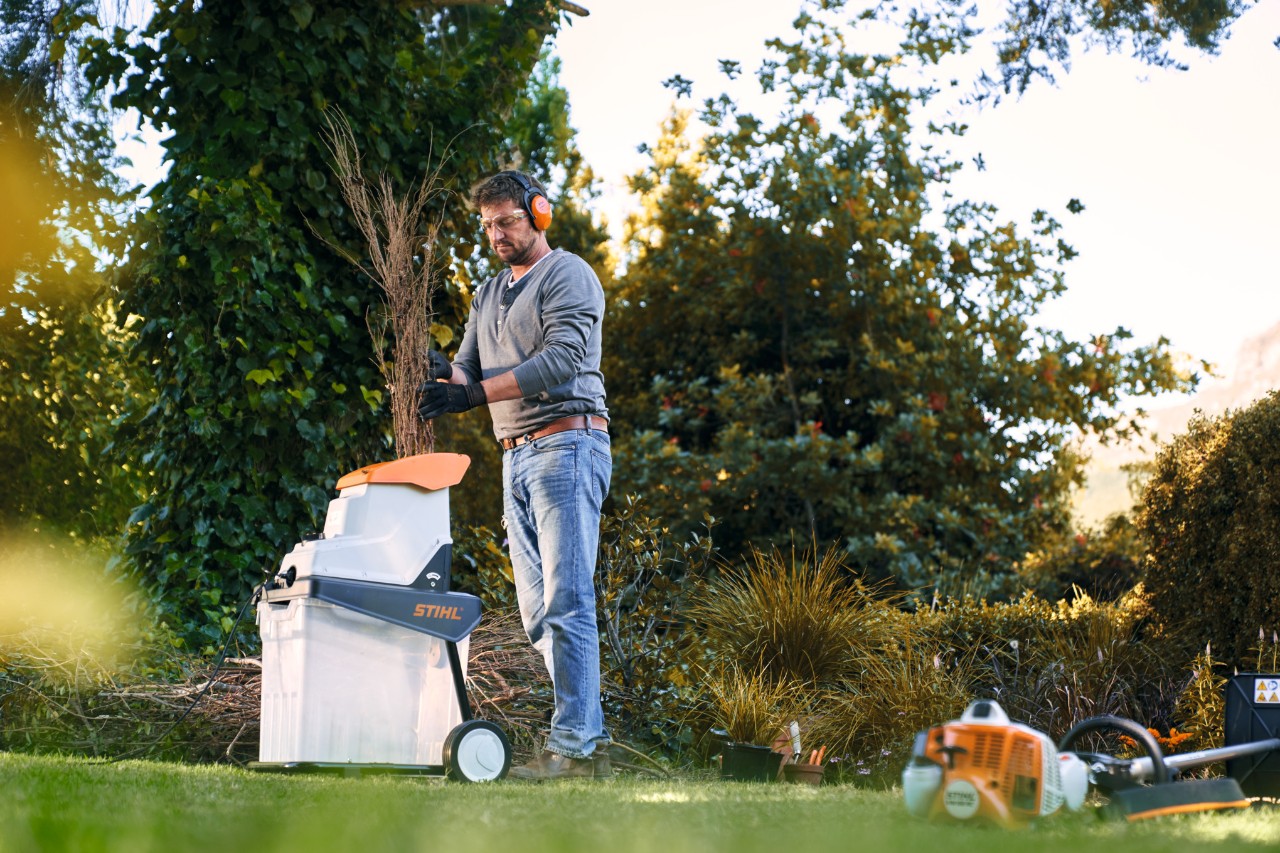 Mann mit STIHL Häcksler im Garten
