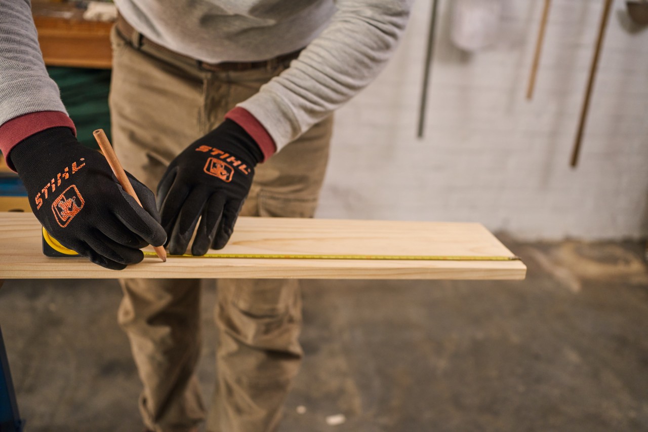 Ein Mann markiert Maße auf einem Holzteil