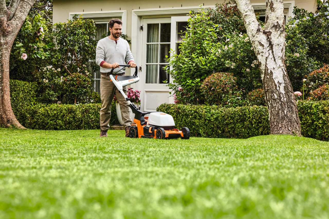 Frau beim Mulchen mit einem STIHL Benzin-Mulchmäher RM 2 R auf einem grünen Grundstück