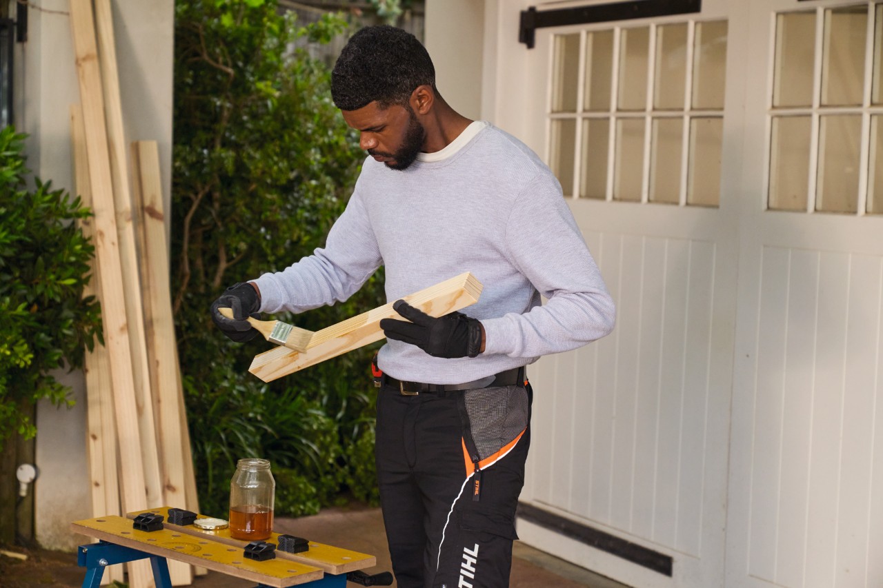 Ein Mann bestreicht ein Holzstück mit Öl