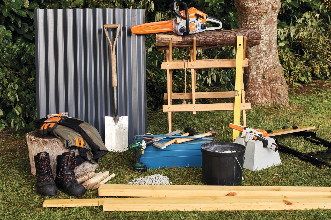 Material und Werkzeug wie die STIHL Akku-Motorsäge MSA 140 liegen im Garten bereit, um Holzunterstand selber zu bauen