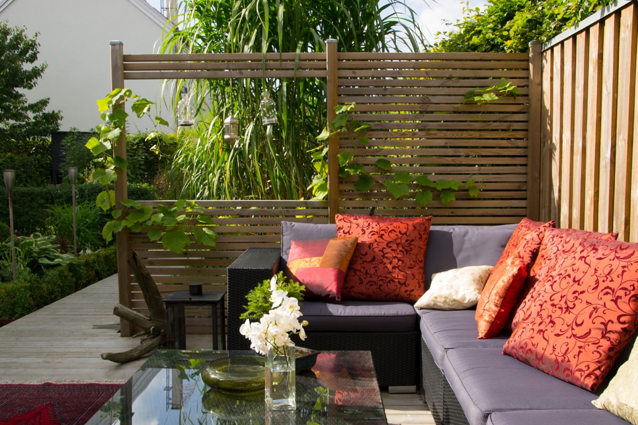Moderne Terrasse mit Couch und einem Sichtschutz aus Holz 
