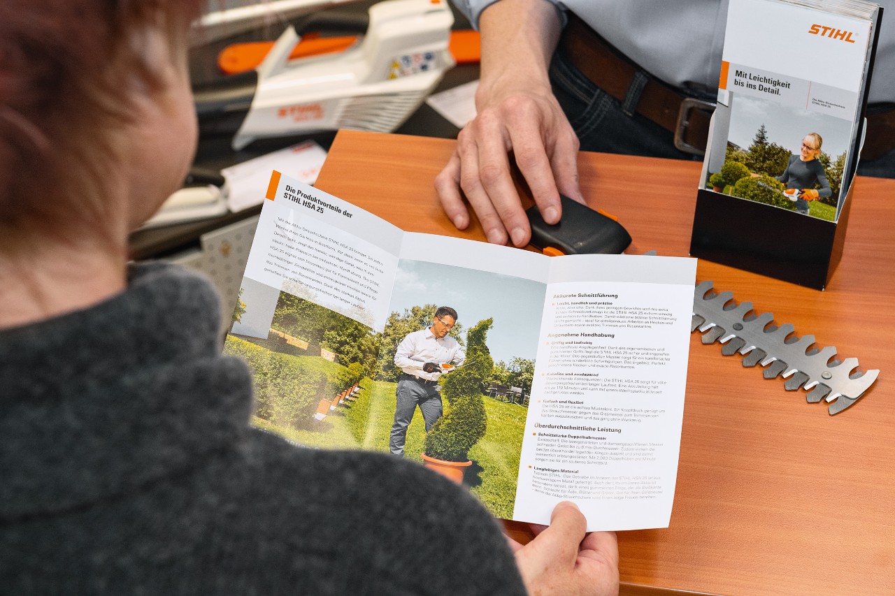 Person schaut sich die Produktvorteile der STIHL HSA 25 in einer Broschüre an
