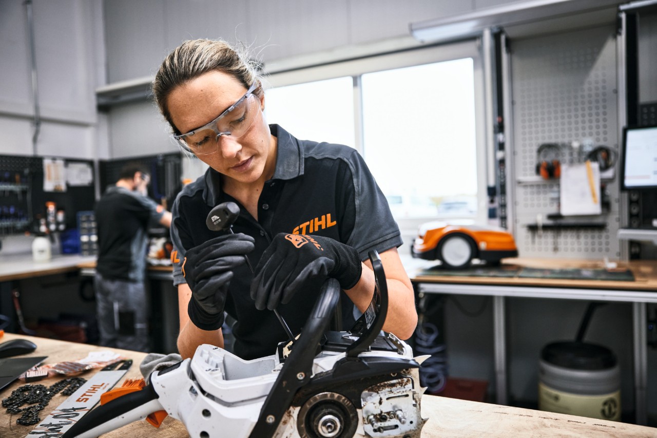 STIHL Mitarbeiterin oder Fachhandelsmitarbeiterin repariert eine Motorsäge